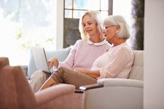 Erwachsene Tochter, die zu Hause älterer Mutter mit Computer hilft Lizenzfreie Stockfotos Erwachsene Tochter, die zu Hause älterer Mutter mit Computer hilft Lizenzfreie Stockfotos