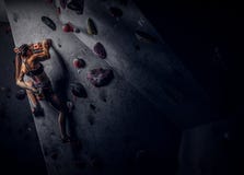 Escalada practicante de la ropa de deportes de la mujer que lleva joven en una pared dentro imagenes de archivo Escalada practicante de la ropa de deportes de la mujer que lleva joven en una pared dentro imagenes de archivo