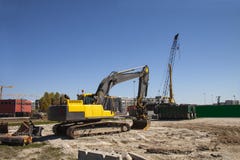 Escavatore al cantiere in costruzione contro il cielo blu - immagine con lo spazio della copia fotografie stock libere da diritti Escavatore al cantiere in costruzione contro il cielo blu - immagine con lo spazio della copia fotografie stock libere da diritti