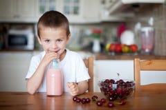 Escolar feliz que bebe un smoothie sano como bocado Imágenes de archivo libres de regalías Escolar feliz que bebe un smoothie sano como bocado Imágenes de archivo libres de regalías