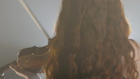 Escuela de la música, del instrumentista que juega en el violín y de vueltas en la iluminación del reflector almacen de metraje de vídeo Escuela de la música, del instrumentista que juega en el violín y de vueltas en la iluminación del reflector almacen de metraje de vídeo