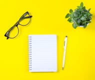 Espace de travail avec le bloc-notes et stylo sur le fond jaune photos stock Espace de travail avec le bloc-notes et stylo sur le fond jaune photos stock
