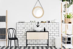 Espejo sobre el lavabo en el interior blanco del cuarto de baño con las plantas y silla negra al lado de la escalera Foto verdade imágenes de archivo libres de regalías Espejo sobre el lavabo en el interior blanco del cuarto de baño con las plantas y silla negra al lado de la escalera Foto verdade imágenes de archivo libres de regalías