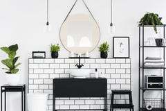 Espejo y cartel sobre el lavabo negro en interior del cuarto de baño con las plantas y las lámparas Foto verdadera imagenes de archivo Espejo y cartel sobre el lavabo negro en interior del cuarto de baño con las plantas y las lámparas Foto verdadera imagenes de archivo