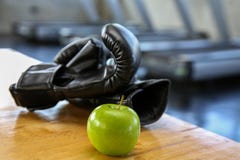 Esporte saudável do estilo de vida Luva de encaixotamento, e alimento saudável em de madeira maçã verde no gym ou no clube de esp imagem de stock royalty free Esporte saudável do estilo de vida Luva de encaixotamento, e alimento saudável em de madeira maçã verde no gym ou no clube de esp imagem de stock royalty free