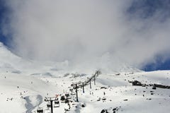 Esquiadores, snowboarders y turistas que usan los teleféricos o el remonte para conseguir al top de una montaña brumosa nevada foto de archivo Esquiadores, snowboarders y turistas que usan los teleféricos o el remonte para conseguir al top de una montaña brumosa nevada foto de archivo