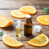 Essential Orange Oil In Bottle, Fresh Fruit Slices On Wooden Background. Natural Fragrances Stock Photos