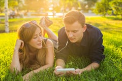 Estate, amore e concetto della gente - vicino su delle coppie adolescenti felici che si trovano sull'erba con le cuffie e che asc Immagine Stock Estate, amore e concetto della gente - vicino su delle coppie adolescenti felici che si trovano sull'erba con le cuffie e che asc Immagine Stock