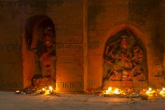 Estatuas antiguas de deidades en la pared con las velas ardientes en la noche imagen de archivo libre de regalías Estatuas antiguas de deidades en la pared con las velas ardientes en la noche imagen de archivo libre de regalías