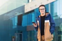 Estudante novo feliz que escuta a música, guardando o telefone fora Copie o espa?o fotos de stock Estudante novo feliz que escuta a música, guardando o telefone fora Copie o espa?o fotos de stock