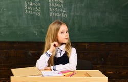 Estudantes atentos que escrevem algo em suas almofadas de nota ao sentar-se em mesas na sala de aula Lição com qualificado imagem de stock Estudantes atentos que escrevem algo em suas almofadas de nota ao sentar-se em mesas na sala de aula Lição com qualificado imagem de stock
