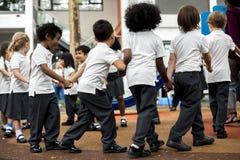 Estudantes do jardim de infância que estão guardando as mãos imagens de stock Estudantes do jardim de infância que estão guardando as mãos imagens de stock