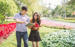 Estudantes felizes que andam e que falam-se em um terreno no parque com uma luz morna fotografia de stock Estudantes felizes que andam e que falam-se em um terreno no parque com uma luz morna fotografia de stock