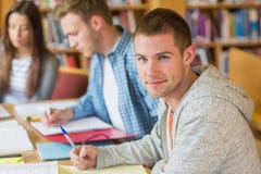 Estudantes que escrevem notas na mesa da biblioteca fotografia de stock Estudantes que escrevem notas na mesa da biblioteca fotografia de stock