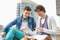 Estudantes universitário masculinas novas felizes que usam a tabuleta digital contra a construção fotos de stock Estudantes universitário masculinas novas felizes que usam a tabuleta digital contra a construção fotos de stock