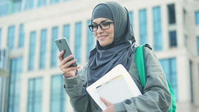 Estudiante de mujer musulmán feliz que charla en el teléfono al aire libre en campus universitario almacen de video Estudiante de mujer musulmán feliz que charla en el teléfono al aire libre en campus universitario almacen de video