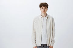 Estúdio disparado do menino europeu considerável e à moda impassível indiferente do moderno nos vidros com posição encaracolado d fotografia de stock Estúdio disparado do menino europeu considerável e à moda impassível indiferente do moderno nos vidros com posição encaracolado d fotografia de stock