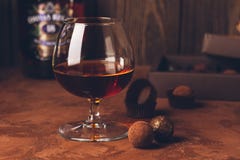 Ett exponeringsglas av stark alkoholdryckkonjak eller konjak och en ask av choklader på en mörk bakgrund kopiera avstånd royaltyfria foton Ett exponeringsglas av stark alkoholdryckkonjak eller konjak och en ask av choklader på en mörk bakgrund kopiera avstånd royaltyfria foton