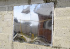 Ett fönster som göras av plexiglas i en betongvägg Ett fönster med en reflekterande klistermärke Royaltyfri Fotografi Ett fönster som göras av plexiglas i en betongvägg Ett fönster med en reflekterande klistermärke Royaltyfri Fotografi