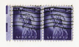 Ett par av amerikanska portostämplar för gammal purpurfärgad tappning med statyn av frihet i Manhattan royaltyfri bild Ett par av amerikanska portostämplar för gammal purpurfärgad tappning med statyn av frihet i Manhattan royaltyfri bild