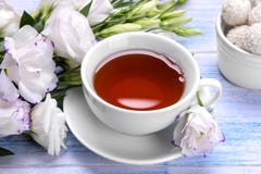 Eustoma белых цветков с чашкой чаю и помадками на голубой деревянной предпосылке стоковые изображения rf Eustoma белых цветков с чашкой чаю и помадками на голубой деревянной предпосылке стоковые изображения rf