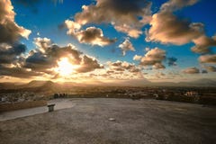 Evening View From The Observation Deck Of Santa Barbara Castle To The City And The Sun In The Clouds Behind The Mountains. Alicant Royalty Free Stock Photography
