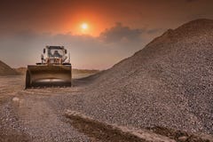 Excavator in a quarry of stone transformation in gravel for the construction of a road stock image Excavator in a quarry of stone transformation in gravel for the construction of a road stock image