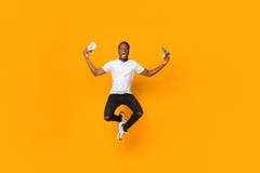 Excited Afro Man Holding Money Jumping In Air, Orange Background Royalty Free Stock Photos