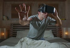 Excited and amazed man wearing VR virtual reality goggles device playing internet 3D simulator game enjoying exciting and stock photography Excited and amazed man wearing VR virtual reality goggles device playing internet 3D simulator game enjoying exciting and stock photography