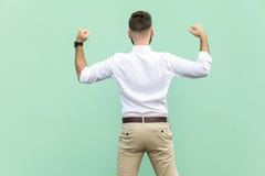 Excited businessman celebrates a career achievement. Back view of a young adult businessman, on light green background. stock photography Excited businessman celebrates a career achievement. Back view of a young adult businessman, on light green background. stock photography
