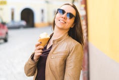 Excited and energetic woman holding ice cream cone in city. stock photo Excited and energetic woman holding ice cream cone in city. stock photo