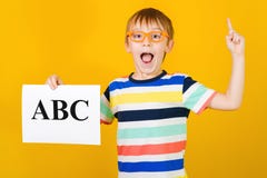 Excited Happy Little Boy Learning Letters. Boy Holds ABC Card Over Yellow Background. Speech Therapist Lessons Royalty Free Stock Photos