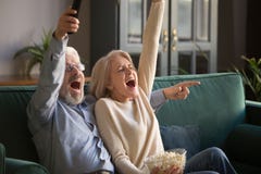 Excited mature couple, man and woman watching football, celebrating victory stock images Excited mature couple, man and woman watching football, celebrating victory stock images