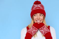 Excited woman looking sideways in excitement. Surprised christmas girl wearing knitted warm hat and mittens, isolated on blue royalty free stock photo Excited woman looking sideways in excitement. Surprised christmas girl wearing knitted warm hat and mittens, isolated on blue royalty free stock photo