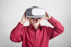 Excited мужской ребенк носит виртуальные изумлённые взгляды relaity, был радостен увидеть фантастические изображения, жизни в дру Стоковое Изображение RF Excited мужской ребенк носит виртуальные изумлённые взгляды relaity, был радостен увидеть фантастические изображения, жизни в дру Стоковое Изображение RF