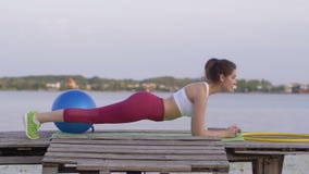 Exercício de Crossfit, mulher bonita forte da aptidão nos esportes que treina a roupa que faz o exercício da prancha na ponte na video estoque Exercício de Crossfit, mulher bonita forte da aptidão nos esportes que treina a roupa que faz o exercício da prancha na ponte na video estoque