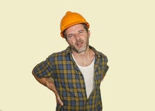Exhausted construction worker or repair man wearing builder helmet complaining suffering pain in his lower back after working hard stock photography Exhausted construction worker or repair man wearing builder helmet complaining suffering pain in his lower back after working hard stock photography