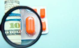 Expensive treatment, medicines and money under a magnifying glass on a blue background stock image Expensive treatment, medicines and money under a magnifying glass on a blue background stock image