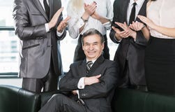 Experienced businessman at the age of applause in the background of their employees royalty free stock image Experienced businessman at the age of applause in the background of their employees royalty free stock image