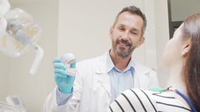 Experienced male dentist talking to his female patient stock footage Experienced male dentist talking to his female patient stock footage