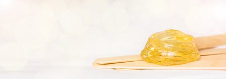 Extra wide banner background with sugar paste or wax honey for hair removing and wooden waxing spatula sticks - depilation and stock images Extra wide banner background with sugar paste or wax honey for hair removing and wooden waxing spatula sticks - depilation and stock images