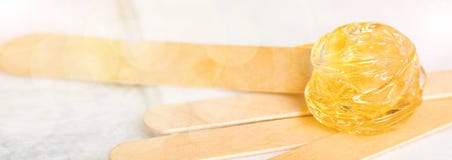 Extra wide banner background with sugar paste or wax honey for hair removing and wooden waxing spatula sticks - depilation and stock photo Extra wide banner background with sugar paste or wax honey for hair removing and wooden waxing spatula sticks - depilation and stock photo