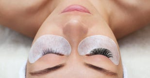 Eyelash removal procedure close up. Beautiful Woman with long lashes in a beauty salon.