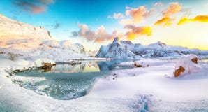 Fabulous frozen Flakstadpollen and Boosen fjords and reflection in water during sunrise with Hustinden mountain on background on
