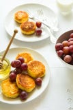 Faccia colazione con le mini torte di formaggio, uva, crema e miele Immagine Stock Libera da Diritti Faccia colazione con le mini torte di formaggio, uva, crema e miele Immagine Stock Libera da Diritti