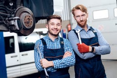 Fadern och sonen arbetar på den auto servicen Två mekaniker arbetar med detaljerna av bilen royaltyfri bild Fadern och sonen arbetar på den auto servicen Två mekaniker arbetar med detaljerna av bilen royaltyfri bild