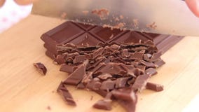 Faites cuire les mains coupant la barre de chocolat avec un couteau de cuisine sur la planche à découper photos stock Faites cuire les mains coupant la barre de chocolat avec un couteau de cuisine sur la planche à découper photos stock