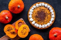 Faites le tarte de potiron Gâteau entier près des potirons sur la vue supérieure de fond noir photographie stock libre de droits Faites le tarte de potiron Gâteau entier près des potirons sur la vue supérieure de fond noir photographie stock libre de droits