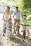 Famiglia che si siede sulle bici sul sorridere del percorso immagine stock Famiglia che si siede sulle bici sul sorridere del percorso immagine stock