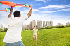 Famiglia felice che gioca aquilone variopinto nel parco della città Immagini Stock Famiglia felice che gioca aquilone variopinto nel parco della città Immagini Stock